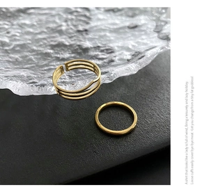 Detail view of a two-piece gold titanium steel geometric ring set on a modern background