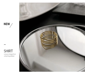 Detail of gold multi-layer open ring with matte finish on a reflective mirror surface