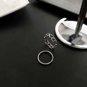 Set of two silver titanium steel rings featuring hollow heart design and minimalist band