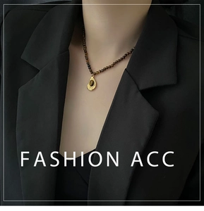 Détail d'un collier vintage en œil de tigre avec pendentif goutte d'eau dorée porté