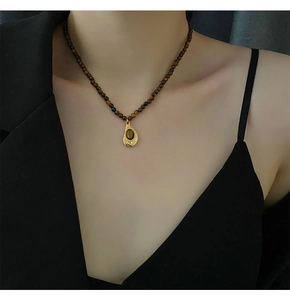 Détail d'un collier vintage en perles d'oeil de tigre avec pendentif goutte dorée