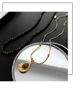 Gros plan du pendentif vintage en pierre œil de tigre et collier avec détails dorés