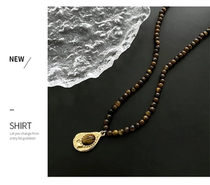 Détail du collier rétro en œil de tigre avec pendentif goutte doré et perles fines
