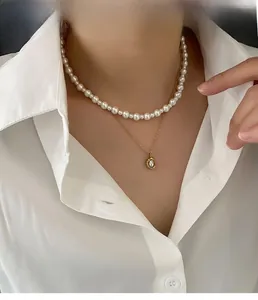Close-up of layered pearl choker and gold chain with pearl pendant on model