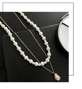 Detail of layered gold titanium necklace with elegant imitation pearls and round pendant