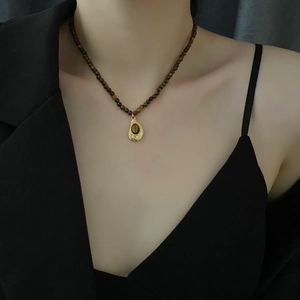 Collier vintage en perles d'œil de tigre avec pendentif goutte d'or sur un mannequin