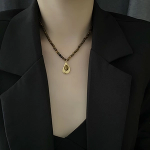 Collier vintage perlé avec pierre œil de tigre et pendentif doré sur un mannequin
