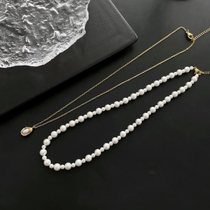 Minimalist pearl and gold pendant necklace set for women on a sleek black stone tray