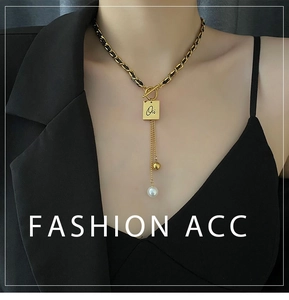Detail of fashion leather chain necklace with square letter pendant and pearl tassels