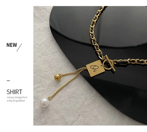 Detail of woven leather gold chain necklace with square letter pendant and pearl tassel