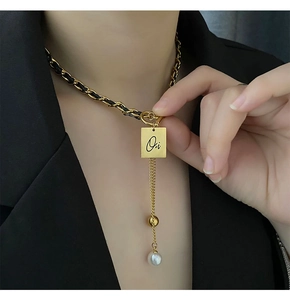 Detail of woven leather chain with golden square pendant and elegant pearl tassel
