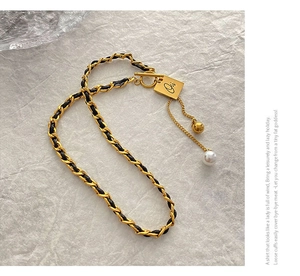 Detailed view of luxury leather chain necklace with gold pendant, pearl, and toggle clasp