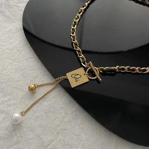 Golden chain necklace with black leather, square letter pendant and pearl tassel detail