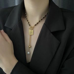 Elegant woven leather and gold chain necklace with a square 'Oui' tag and pearl drop