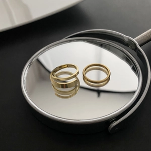 Detailed macro of polished gold adjustable spiral rings reflecting on a mirror