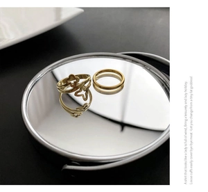 Macro shot of gold-toned titanium rings with clover cutout on a reflective mirror base