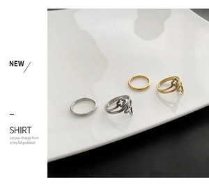 Detailed close-up of four minimalist gold and silver clover rings on a white porcelain dish