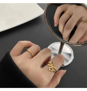Detail view of gold clover ring set on model's hand with creative mirror reflection
