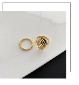 Detailed macro of a two-piece gold plated ring set featuring a geometric hollow mesh design