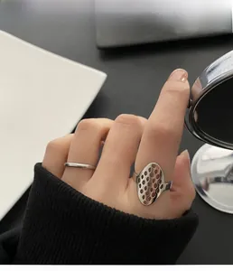 Detail of silver geometric hollow honeycomb ring and minimalist band on model hand
