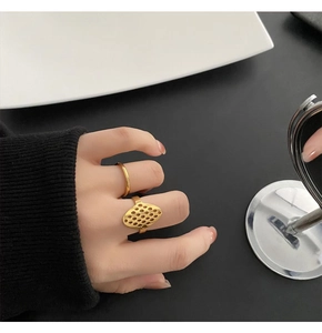 Close-up of geometric hollow 18k gold plated titanium ring set worn with black knitwear
