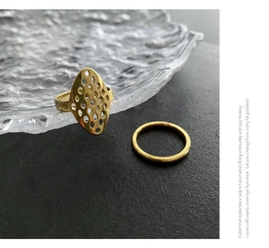 Detailed macro of two gold hollow geometric rings with honeycomb texture in 18k gold plating