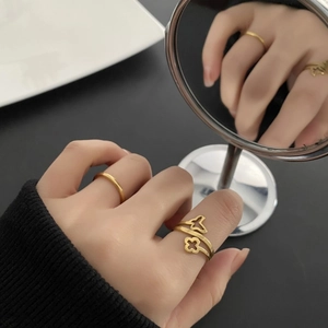 Gold titanium four-leaf clover ring set with minimalist bands shown on hand with mirror