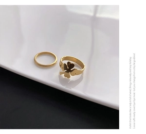 Detail of a two-piece gold clover ring set with a minimalist band on a white display tray