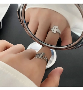 Creative mirror reflection of a silver four-leaf clover open ring with hollowed petals