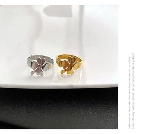 Macro view of minimalist clover heart rings in polished gold and silver steel finish