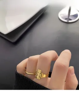 Close-up of gold four-leaf clover ring with hollow heart design worn by a model
