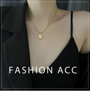Close-up of a French style gold necklace with oval mother of pearl pendant on a model