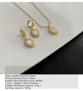 Detail of gold titanium steel necklace and earrings set with white mother of pearl inlays