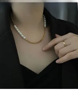 Detail of trendy gold chain and pearl necklace paired with a matching gold band ring