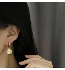 Macro view of vintage-style earrings featuring white mother-of-pearl and gold rope texture