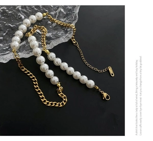 Detail of chunky gold Cuban chain and white faux pearl necklace with lobster clasp