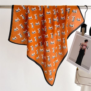Detail of orange silk scarf with horse print hanging by a white handbag and card