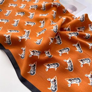 Macro shot of orange horse pattern silk scarf with black border and twill weave texture