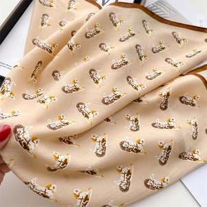 Close-up of warm beige silk-feel scarf with detailed brown cat animal print and twill texture