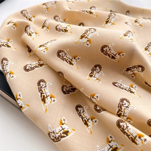 Macro detail of twill silk scarf with cute calico cat and orange print on beige fabric