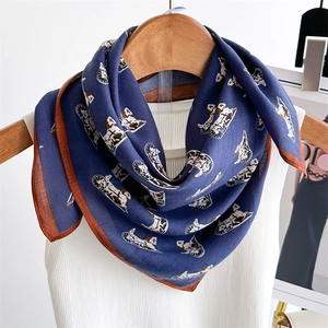 Detailed close-up of dark blue silk scarf with vintage carriage print and brown hem