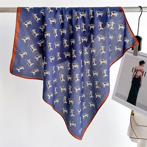 Detailed view of navy blue square scarf with animal print and brown stitched edges