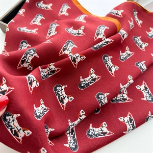 Detail of herringbone silk scarf in deep red with orange borders and horse patterns