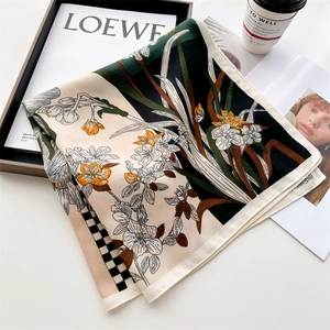 French floral silk scarf with daffodil print and checkerboard pattern on magazine box