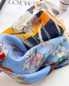 Detailed macro view of floral print silk scarf with herringbone texture on a white table