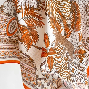 Dettaglio di un foulard in seta con stampa leopardata della giungla e bordi arancioni