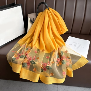 Detail of yellow silk scarf with floral embroidery, organza trim and pearl accents
