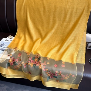 Detail of golden silk scarf featuring floral embroidery and grey organza border trim