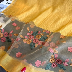 Macro detail of yellow silk scarf featuring floral embroidery and 3D beadwork accents