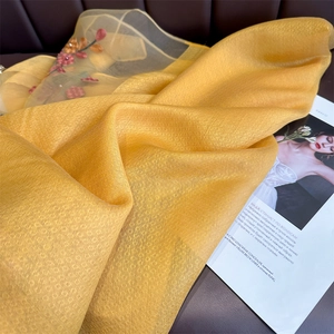 Close-up of yellow silk scarf featuring intricate jacquard texture and floral embroidery
